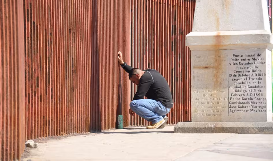 A man says goodbye to his partner through the border fence