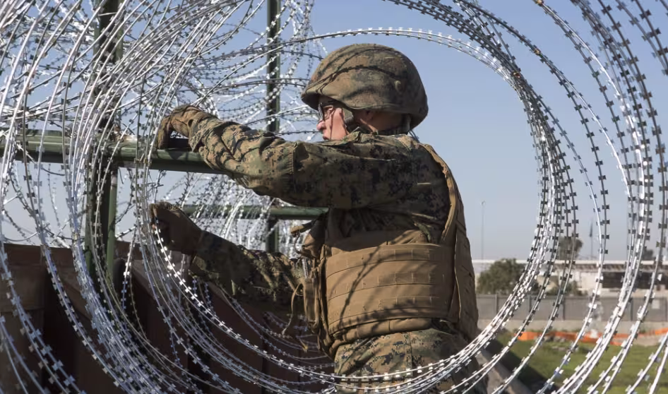 U.S. Marine secures barbed-wire fencing at the California-Mexico border.