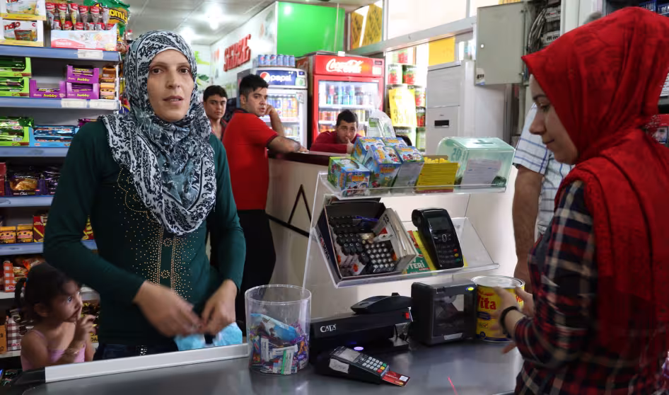 A Syrian refugee woman uses a special e-card to purchase food at a grocery store in Turkey. 