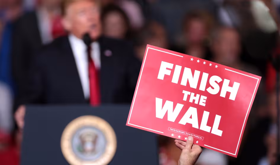 A supporter holds a sign reading "Finish the Wall" during a rally for President Donald Trump in Mesa, Arizona.