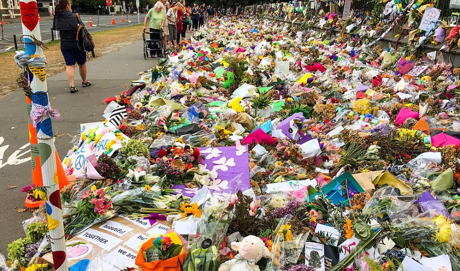 People pass by flowers laying on a street