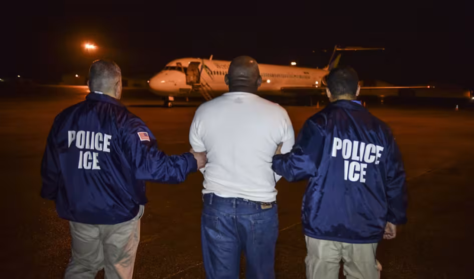 A migrant scheduled to be deported from the United States is escorted to a charter flight. 
