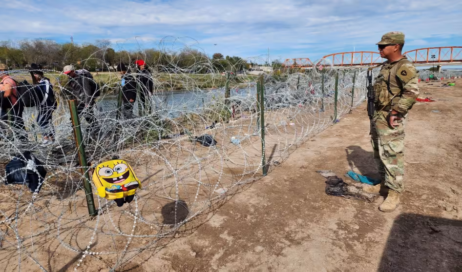 A member of the Texas National Guard faces migrants in Eagle Pass, Texas.