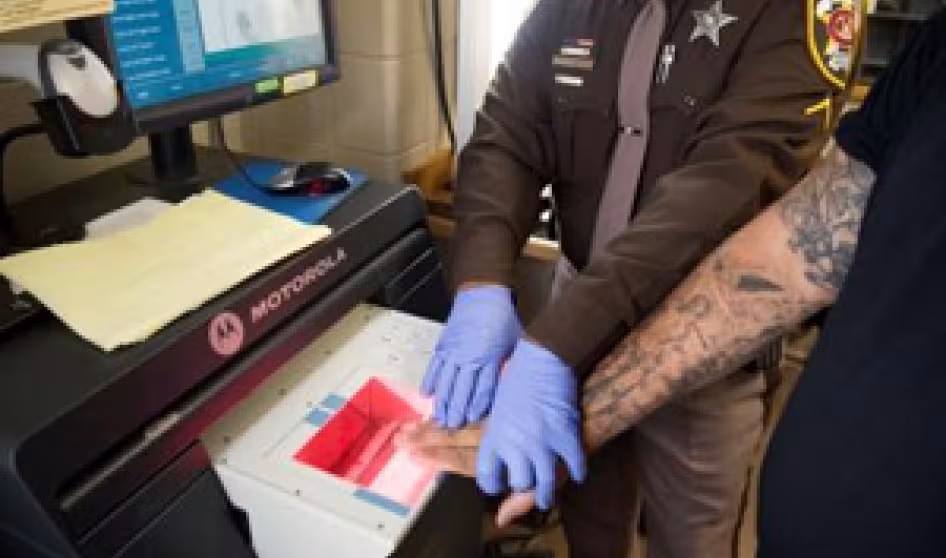 An office checks arrestees' fingerprints against criminal and immigration databases.