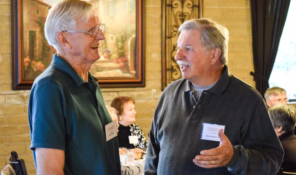 Two men talk during a retiree luncheon