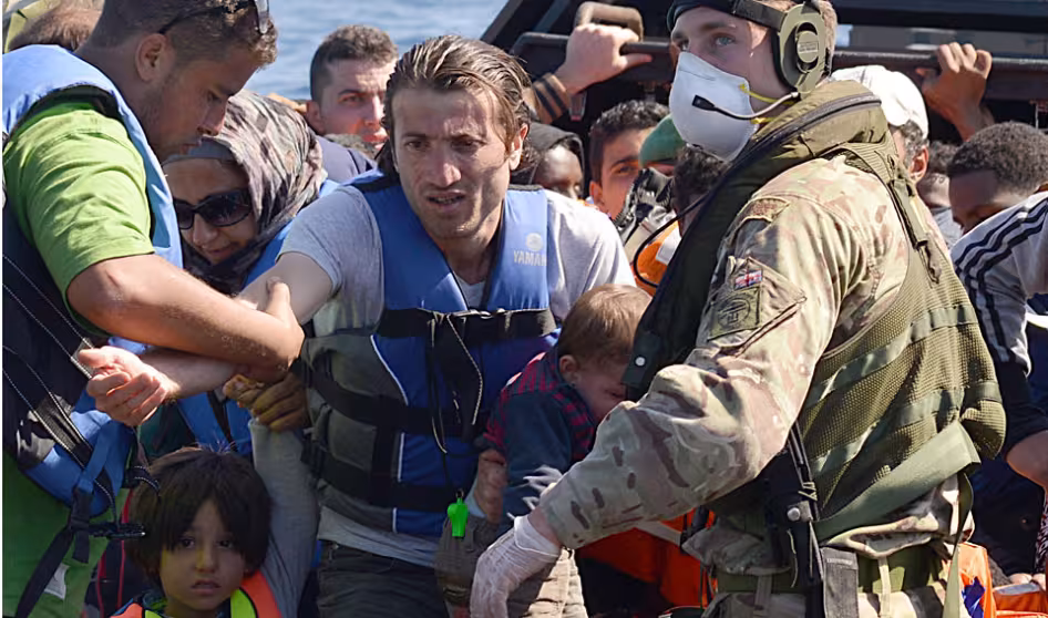Sailors and marines on the HMS Bulwark help migrants ashore in Italy.