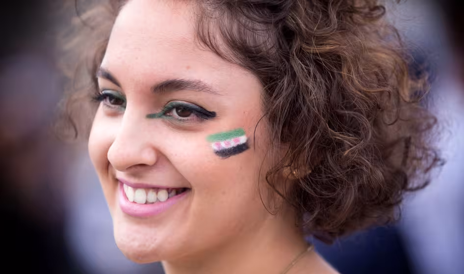 A young woman with the Syrian flag painted on her cheek