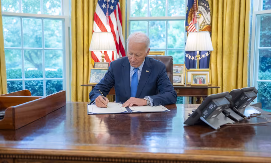 President Joe Biden signs a bill in the Oval Office