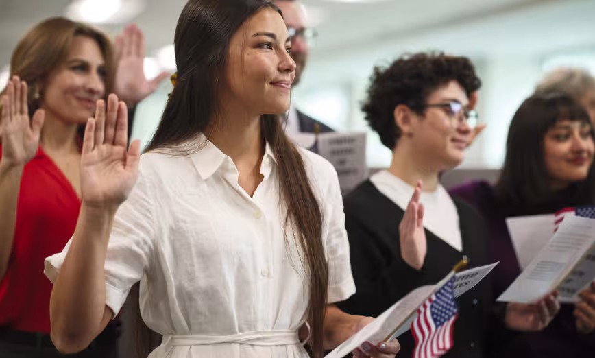 A line of people with their hands up taking the oath during a U.S. citizenship ceremony