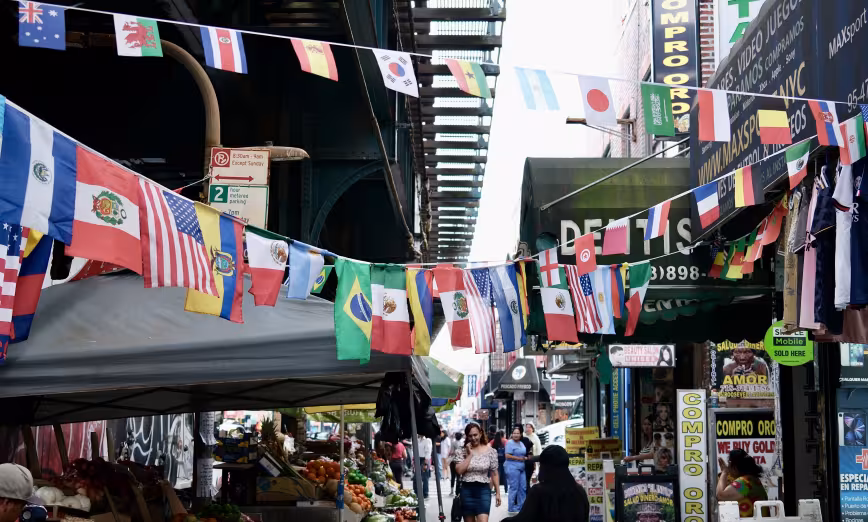 The flags of various countries hang above storefronts in an urban environment 