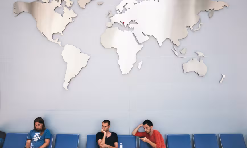 People waiting underneath a large metal map of the planet