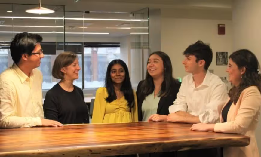Interns and staff standing around a table