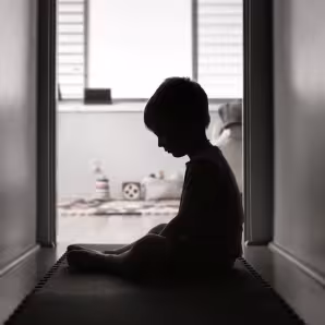 A silhouette of a young child looking sad and alone
