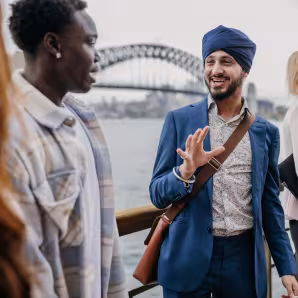 People of different ethnic backgrounds engage in a lively discussion, against the backdrop of Sydney Harbour Bridge