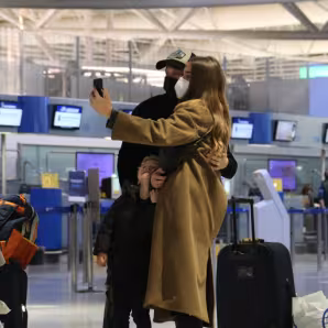 People wearing face masks take a selfie at an airport