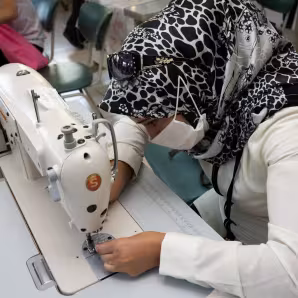 A woman in a headscarf leaning over a sewing machine.