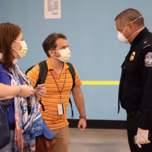 Officer and travelers wearing PPE at Port Everglades, Florida