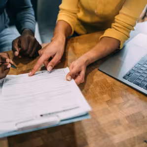 Image of the hands of two people at a desk going over paperwork
