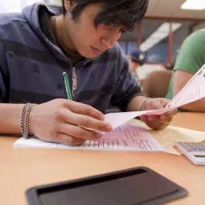 Student looking over a paper at a desk