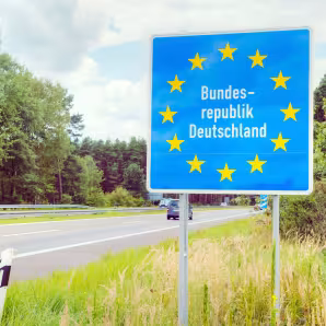 A German border sign next to a road
