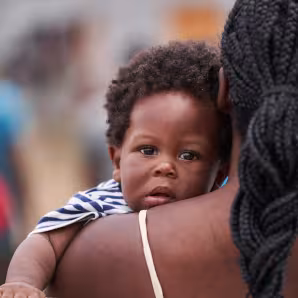 A Haitian child looks over his mother's shoulder in Panama