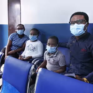 Two adults and two children wearing face masks at a migration health centre in Nigeria