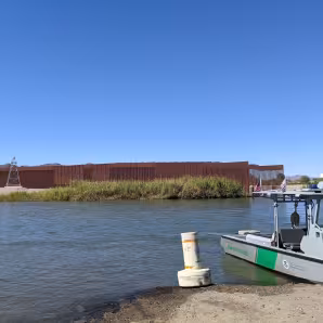 Image of U.S.-Mexico border wall and Border Patrol boat