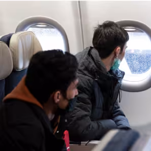 Two people on an airplane looking out the window