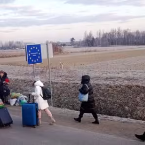 Ukrainians walking on the road with luggage into an EU area 