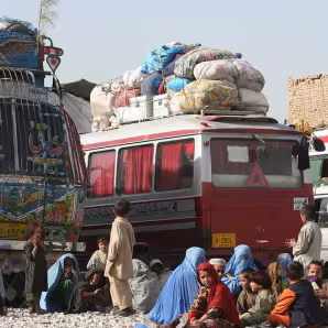 Returned Afghan refugees wait by the buses in Kabul that will take them back home.