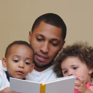 An immigrant father reading with his children.