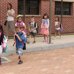 Young students walking with their teacher.