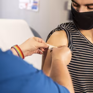 A health-care provider places a bandage on the injection site of a patient who just received a vaccine.