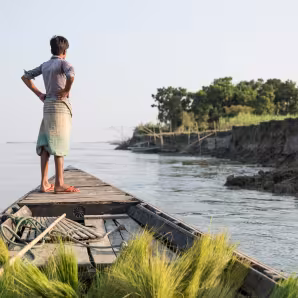A boy on a boat in a Bangladeshi community affected by river erosion