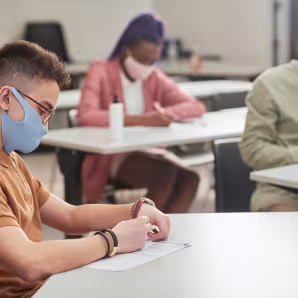 Side view portrait of young man and two other students taking a test