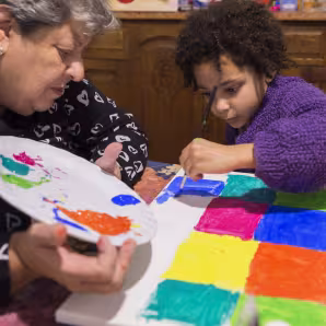A grandmother and young grandchild painting at home