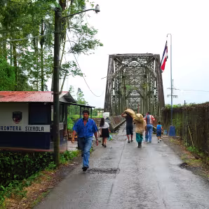 People walking across the bridge over the Sixaola River at the border between Panama and Costa Rica