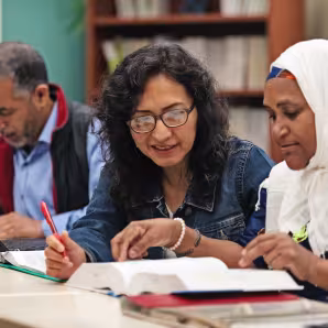 Immigrant adults working together at a long table in a classroom