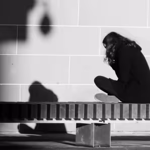 Girl sitting on a bench facing a wall