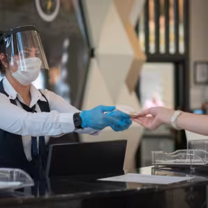 Receptionist wearing personal protective equipment while interacting with a customer