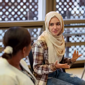A college student in a hijab talks to another woman