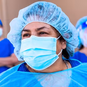 Three health-care workers wearing blue protective masks and gowns