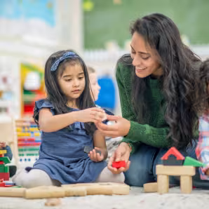 A teacher and group of young children play with blocks