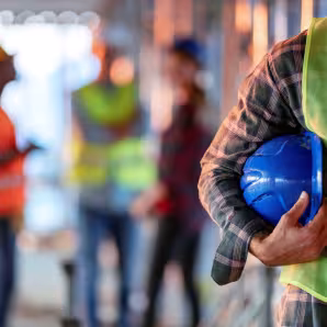 Construction worker holding a blue hard hat.