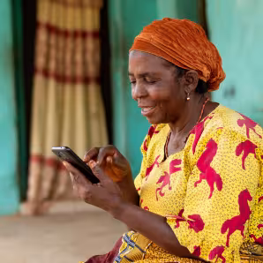 A woman in Nigeria smiles while using her mobile phone
