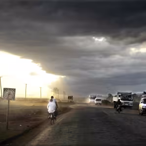 Motorbikes and cars travel down a road in a storm