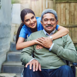  A young nurse hugs an elderly patient in a wheelchair