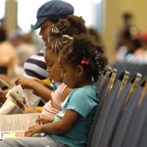 A woman and three children sit on a bench reading.