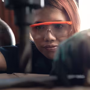 A young woman operating an industrial drilling machine