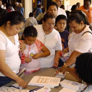 Parents and their children talk to another adult seated at a table at a Parents & Family Conference